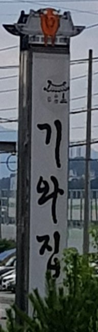 길가에 선 세로 간판 «기와집»