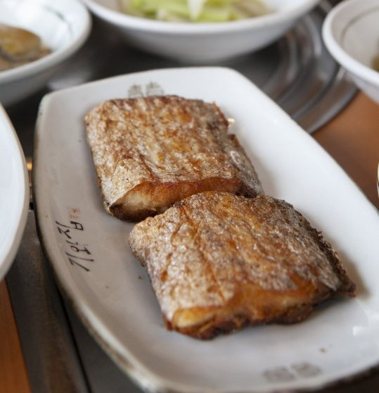 «기와집» 글씨가 찍힌 흰 접시에 담은 갈치구이