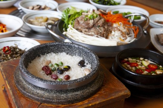 앞에 돌솥밥, 뒤에 불고기전골, 오른쪽에 검은 냄비